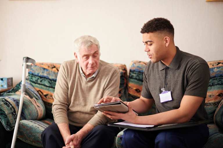 Social worker speaking to elderly client on couch
